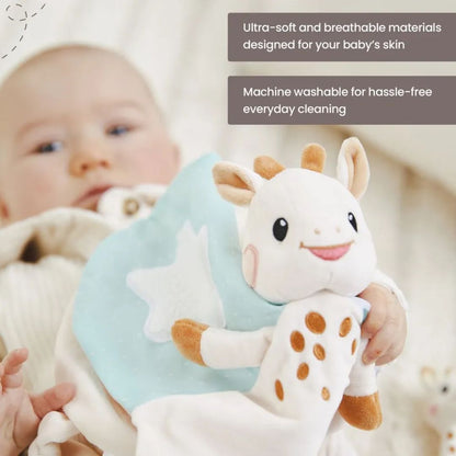 Close-up of a baby holding the Sophie la Girafe comforter with its plush giraffe head and spotted corner visible, with text reading 'Ultra-soft and breathable materials designed for your baby's skin' and 'Machine washable for hassle-free everyday cleaning.