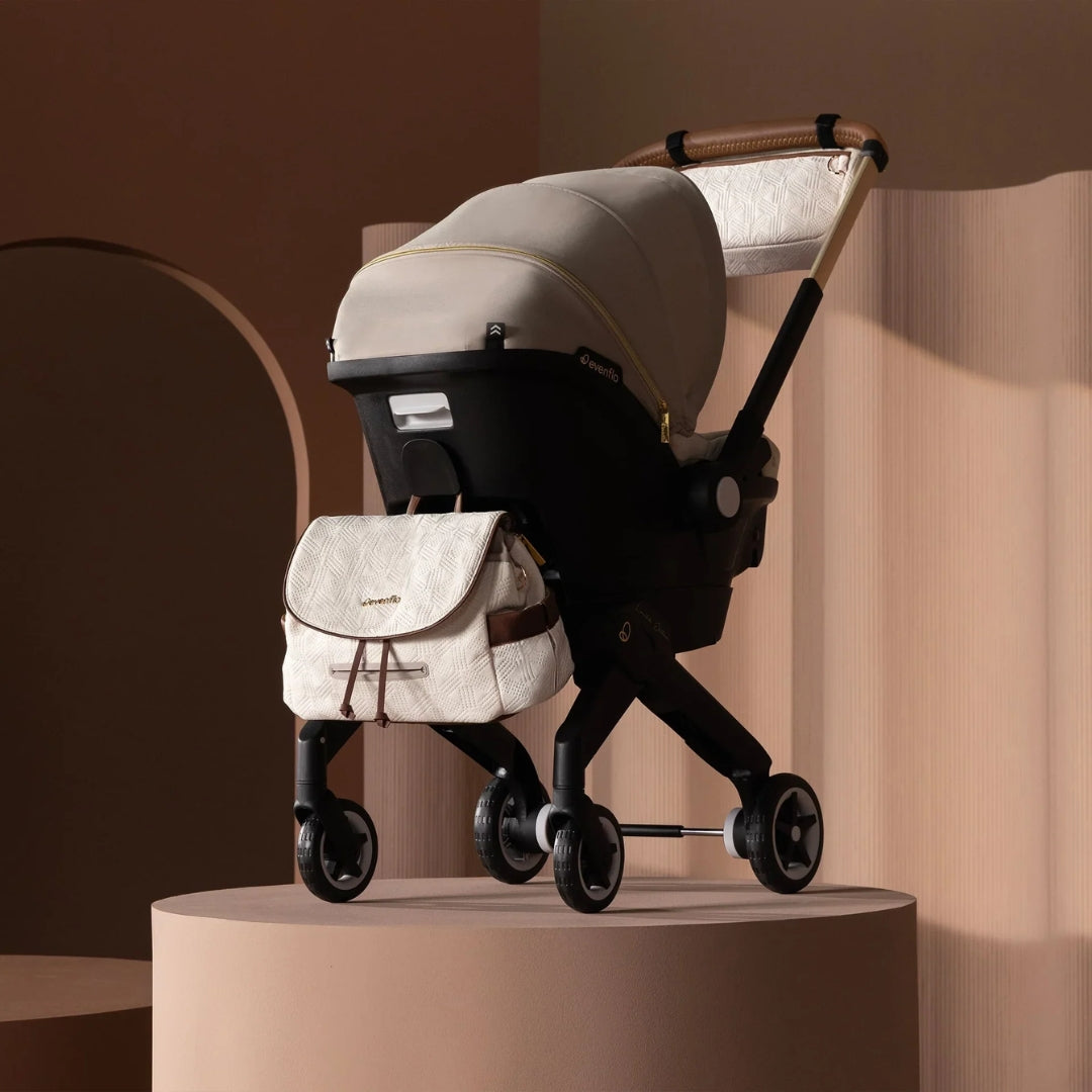Evenflo Beige stroller with matching bag on a beige platform against a warm-toned background