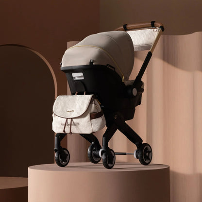 Evenflo Beige stroller with matching bag on a beige platform against a warm-toned background
