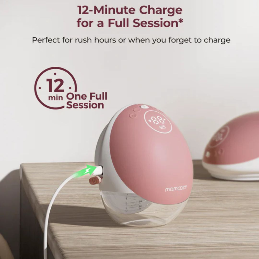 Pink electronic momcozy breast pump with charging cable on a wooden surface, featuring text about charging time.