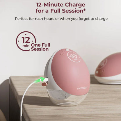 Pink electronic momcozy breast pump with charging cable on a wooden surface, featuring text about charging time.