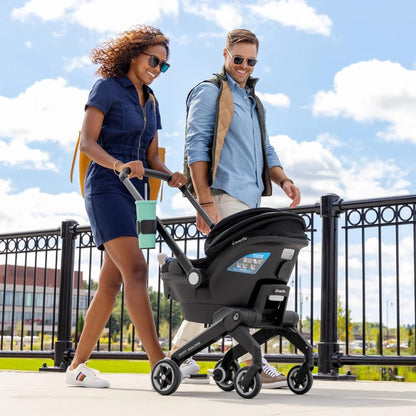 Man and woman pushing an Evenflo stroller together outdoors on a sunny day.